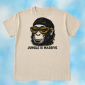 A beige crewneck t-shirt featuring a graphic of a chimpanzee wearing yellow-tinted goggles with the text 'JUNGLE IS MASSIVE' printed below, displayed against a light blue cloudy background.