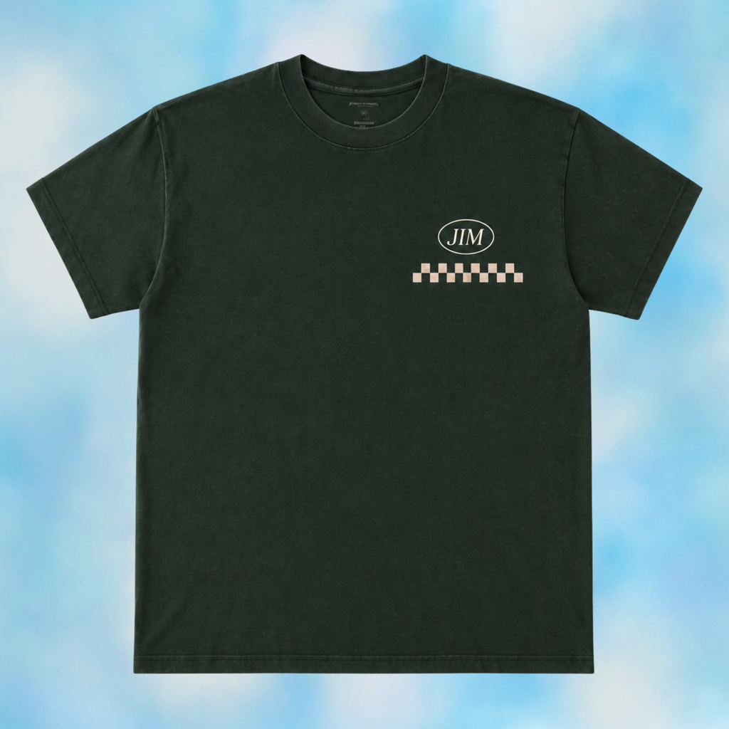 A dark charcoal gray crewneck t-shirt with a small chest graphic featuring a white oval 'JIM' logo above a checkered stripe, set against a light blue and white cloudy background.