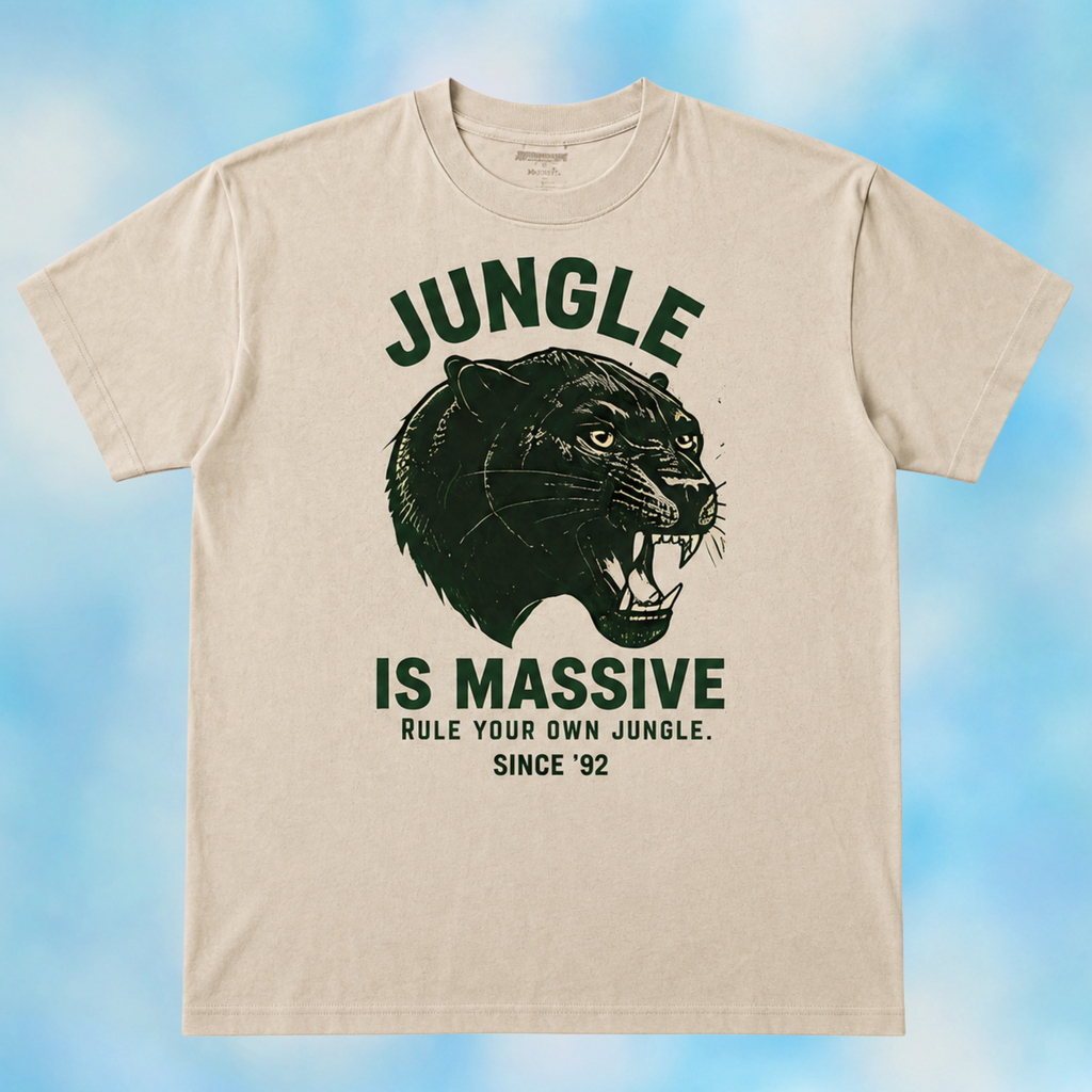A beige crewneck t-shirt with a dark green graphic print of a roaring jaguar and the text 'JUNGLE IS MASSIVE' on the front, displayed against a soft blue and white cloudy background.